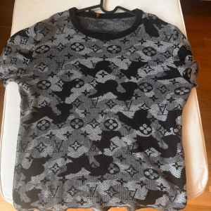 Grå och svart mönstrad stickad tröja - Säljer en grå och svart stickad tröja Louis Vuitton. Tröjan har långa ärmar och är perfekt för dig som gillar grafiska detaljer och en bekväm passform. Storleken L. Skick är gangska ny 