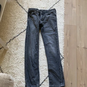 Svarta slim-straight jeans från Jack & Jones - Tja Säljer ett par svarta jeans från Jack & Jones med slim-straight passform storlek 28/32. Klassisk femficksmodell med dragkedja och knapp i midjan. Perfekta till vardags och passar till det mesta. Snygg tvättad look och bekvämt material.