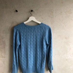 Ljusblå kabelstickad tröja från Polo Ralph Lauren - Säljer en ljusblå kabelstickad tröja från Polo Ralph Lauren. Tröjan har rund halsringning, lång ärm och klassisk kabelstickad struktur. Liten broderad logga på bröstet. Perfekt för en stilren och avslappnad look. Knappast använd