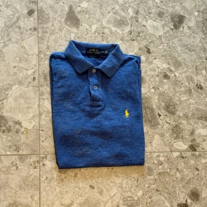 Blå pikétröja från Polo Ralph Lauren - Säljer en klassisk blå pikétröja från Polo Ralph Lauren. Gjord av bomull och har inte tvättats därav av priset. Nypris cirka 1500kr