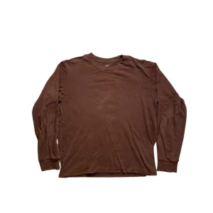 Uniqlo tröja - Säljer en enkel och stilren brun långärmad tröja från Uniqlo. Tröjan har rund halsringning och är tillverkad i mjuk bomull, perfekt för lager-på-lager eller som den är. Passar dig som gillar en klassisk och avslappnad look. Tröjan har dock en fläck vid halsringen, fast fläcken syns bara när man kollar väldigt noga. Det finns en annan liknande Uniqlo tröja som är till salu som hittas i profilen.