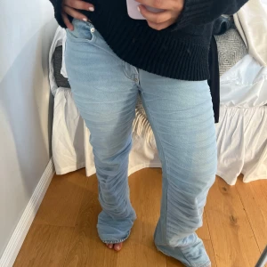 Jeans - Säljer ett par ljusblå jeans med bootcut passform och snygga rynkade detaljer längs hela framsidan. Jeansen har klassisk femficksdesign och normalhög midja. Perfekta för dig som vill ha en trendig och unik look. W27