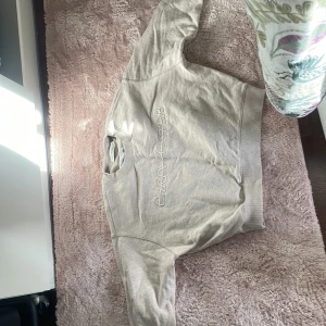 Beige sweatshirt från Carin Wester - Säljer en beige sweatshirt från Carin Wester med broderad logga framtill. Tröjan har rund halsringning och långa ärmar. Perfekt för en avslappnad och stilren look.