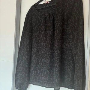 En svart blus med mönster  - Säljer en svart blus med mönster.