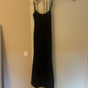 Svart långklänning med smala axelband från Bershka - En stilren svart långklänning från Bershka med smala axelband. Klänningen har en tight passform. Klänningen är nopprig men annars är den i fint skick.🩷