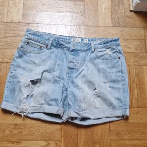 Jeansshorts  - Jeansshorts med knappar och slitna detaljer i strl 40 från Cubus. Katt i hemmet.