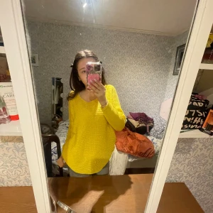 Gul stickad tröja med v-ringning - Säljer en solgul stickad tröja med v-ringad hals. Tröjan är mjuk och har en avslappnad passform med långa ärmar. Perfekt för att liva upp garderoben med lite färg! Materialet är 100% akryl.