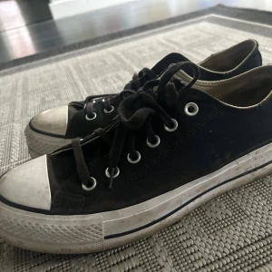 Svarta Converse -använt skick  - Klassiska svarta sneakers med vit sula och tå, samt svarta snören. Skorna har lågt skaft och silverfärgade öljetter. Perfekta för en avslappnad stil och passar till det mesta.