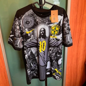 Brasilien fotbollströja - Unik svart och grå Brasilien fotbollströja med Neymar JR och nummer 10. Framsidan har ett detaljerat grafiskt mönster med Brasilien-emblem. Korta ärmar och Nike-logga. Perfekt för dig som vill vara stilig en solig sommardag helt oanvänd med tagg och allt