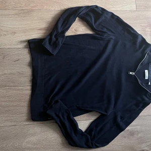 Half zip tröja - Säljer en svart stickad tröja från Jack & Jones med dragkedja vid halsen. Tröjan har lång ärm och är i en klassisk, normal passform. Perfekt för lager-på-lager och enkel att matcha med olika outfits.