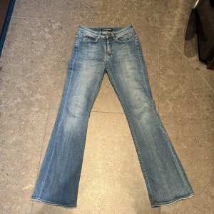 Ljusblå bootcut jeans  Drykorn stl 28/32 - Säljer ett par ljusblå jeans från Drykorn med klassisk femficksdesign och bootcut-ben. Jeansen har normal passform och är tillverkade i denim med lätt slitning framtill. Stl 28/32