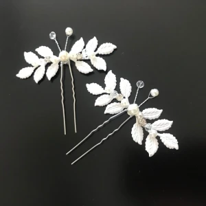 Vita hårnålar med pärlor och blad - Två eleganta hårnålar dekorerade med vita blad och pärlor samt små glittriga stenar. Perfekt accessoar för att ge håret en extra touch vid speciella tillfällen. Ny 