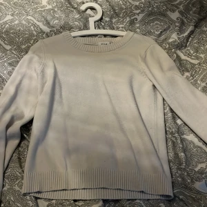 Vit stickad tröja från VILA - Mysig vit stickad tröja från VILA med rund halsringning och ribbade muddar vid ärmslut och nederkant. Perfekt för lager-på-lager och enkel att matcha med olika outfits. Defekter förekommer, kolla dem givna bilderna.