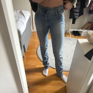 Ljusblå  lågmidjade jeans - Säljer ett par ljusblå jeans med klassisk femficksdesign och normal passform. Byxorna har lägre midja, raka ben och stängs med dragkedja och knapp. Perfekta till vardags och lätta att matcha med olika toppar. Väldigt stretchiga i materialet