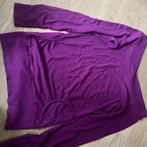 Lila stickad tröja från clovis - Säljer en lila stickad tröja från clovis med breda ribbade muddar vid ärmslut och nederkant. Tröjan har lång ärm och en avslappnad passform, perfekt för kyligare dagar.