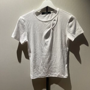 Vit ribbad topp med cut-out från BikBok - vit ribbad topp från BikBok med korta ärmar och unik cut-out detalj framtill med knapp. 