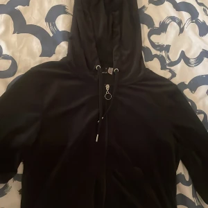Svart Velour kofta med dragkedja från Gina Tricot - Svart kofta med dragkedja och huva från Gina Tricot. Koftan har snörning i huvan och en rund metallring som dragkedjedetalj. Perfekt för en avslappnad stil.