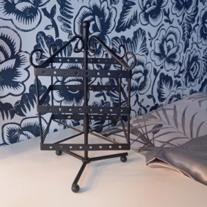 Svart smyckeshållare i metall - Snygg svart smyckeshållare i metall med tre våningar och många hål för att hänga örhängen. Står stadigt på tre ben och har dekorativa detaljer upptill. Perfekt för att organisera och visa upp dina smycken på ett stilrent sätt.  Om priset är för högt är det bara att skicka ett bud.