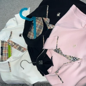 Burberry pikétröjor med rutiga detaljer - Tre klassiska pikétröjor från Burberry i svart, vit och ljusrosa. Tröjorna är sparsamt använda. Tyvär är dem inte äkta men snygga oavsett. Om man ska köpa dem måste man köpa alla