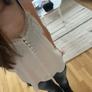 Ljusrosa topp/linne med spets och knappar - Säljer en söt rosa/beige linnetopp med tunna axelband, spetsdetaljer och dekorativa knappar💋💋 Perfekt för varma dagar och enkel att matcha med jeans eller kjol. Funkar både till festligare tillfällen och skola! Knappt använd🥰