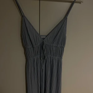 Ljusblå topp med smala axelband - Säljer en ljusblå plisserad blus/topp från Zara med smala axelband och knytning framtill. 