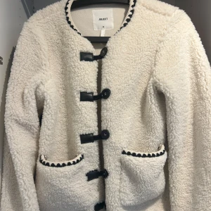 Vit teddyjacka från Object - Säljer en vit teddyjacka från Object med svarta detaljer och coola knappar framtill. Perfekt för dig som vill ha en mysig, trendig men unik look nu när det börjar bli kallare! Nypris: 1199. Slutsåld. Knappt använd💞💞