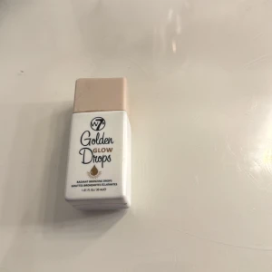 W7 Golden Glow Drops bronzer - Golden Glow Drops från W7 är flytande bronzer i en smidig vit plastflaska med beige lock. Ger en strålande solkysst finish och kan blandas med foundation eller användas direkt på huden för extra glow. Innehåller 30 ml och är perfekt för att skapa en fräsch, gyllene look.