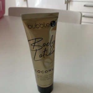 Bubble T Body Lotion Coconut 100ml - Bubble T Body Lotion med kokosdoft i en snygg guldskimrande tub på 100ml. Tuben har svart skruvlock och är gjord av plast. Perfekt för att återfukta huden och ge en fräsch känsla med tropisk doft. Enkel att ta med i väskan och applicera när som helst.