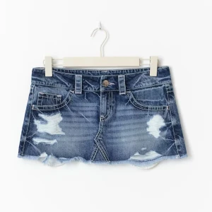 Blå jeanskjol med slitningar Gina Tricot  - Den trendiga jeanskjolen från Gina Tricot i storlek XS. Lågmidjad i blå denim med slitna detaljer och fransad nederkant. 