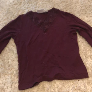 Vinröd långärmad topp med spets Gina Tricot - Supersnygg vinröd långärmad topp från Gina Tricot med v-ringning och dekorativ spetsdetalj framtill. Mjuk och skön bomullskänsla, perfekt för dig som gillar stilrena plagg med en twist. Passar dig som vill ha en enkel men ändå cool look.
