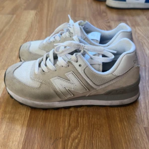 New Balance 574 sneakers  - Säljer ett par New Balance 574 sneakers i beige och vitt i storlek 36,5. Använda men i fint skick. 