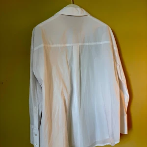 Vit klassisk skjorta från F&F - Snygg vit skjorta från F&F med klassisk krage och knappar framtill. Skjortan har lång ärm med bred manschett och är tillverkad i mjuk bomull. 