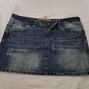 Mörkblå jeanskjol medellång  - Fin jeanskjol yk2 style. Lite detaljer på bakfickorna och orangea detaljer. Köpt från en marknad i Thailand.