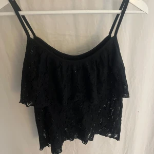 Svart spetsig linnetopp från Bik Bok - Svart linnetopp från Bik Bok med tunna axelband och snygg spetsdesign. Toppen har ett lager med volang framtill. Vardaglig men ändå lite extra! 