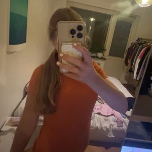 Orange kortärmad tröja - Säljer en enkel och snygg orange tröja med korta ärmar. Modellen är figurnära och har en klassisk rund halsringning. Perfekt för dig som gillar färg och vill ha en stilren look. Passar dig som vill ha en bekväm och trendig tröja.