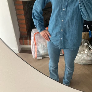 Blå bootcut jeans från MNG Denim - Snygga ljusblå jeans från MNG Denim med klassisk bootcut passform. Jeansen har två bakfickor, gul kontrastsöm och broderad logga bak. Tillverkade i mjukt denimtyg som sitter skönt och ger en chill vibe. Perfekt för dig som gillar retrostil och vill sticka ut.