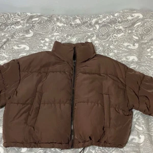 Brun croppad pufferjacka från H&M - Säljer en brun croppad pufferjacka från H&M Divided i storlek M. Jackan har hög krage, dragkedja framtill och två sidofickor. Perfekt för dig som gillar en loose och trendig look under höst och vinter. Säljer då jag aldrig använt den och den mest bara legat och dammat 