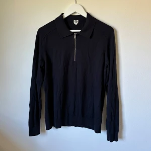 Mörkblå half zip tröja från ARKET - Marinblå långärmad tröja från ARKET i storlek M. Tröjan har en klassisk krage och en snygg half zip-dragkedja framtill. Materialet är mjukt och känns som bomull, perfekt för dig som gillar stilrena och enkla plagg. Passformen är normal och funkar till många olika looks. 1A4