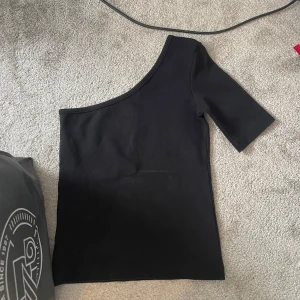 Svart oneshoulder topp - Snygg svart topp med oneshoulder. Storlek s.