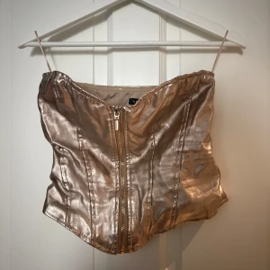 Guldig korsett  - Snygg guldig korsett från Amisu i storlek M. Toppen har en metallic finish och dragkedja framtill. Använd en gång