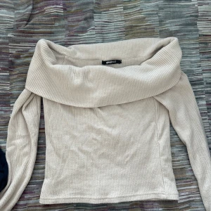 Beige ribbad offshoulder tröja Gina Tricot - Säljer en beige ribbad offshoulder tröja från Gina Tricot. Tröjan har långa ärmar och en bred krage som sitter snyggt över axlarna. Perfekt för dig som gillar stilrena och trendiga plagg med lite extra edge. ALDRIG ANVÄND