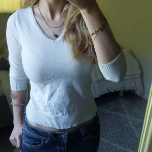 Vit v-ringad stickad tröja - Vit stickad tröja köpt på ullared med v-ringad hals och trekvarts ärmar. Tröjan har ribbade muddar vid ärmslut och nederkant. Säljer då den inte kommer till användning längre.