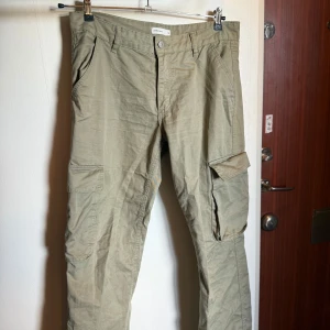 Beige cargopants från Perfect Jeans - Snygga beige cargopants från Perfect Jeans med raka ben och flera praktiska fickor på sidorna och bak. Byxorna har normal passform och är tillverkade i mjuk bomull. Perfekt för dig som gillar streetstyle och vill ha en avslappnad look.