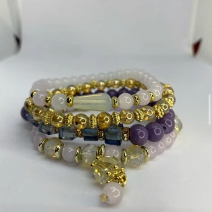 Färgglada pärlarmband med guldton - Säljer ett set med flera pärlarmband i lila, blått, vitt och guld. Armbanden har olika former på pärlorna, blandat med runda och facetterade pärlor samt guldfärgade detaljer. Ej använd utan kommer från min small business. 