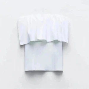 Vit bandeau tubtopp med volang - Säljer en fräsch vit bandeau tubtopp med bred volang upptill. Toppen är axelbandslös och har en croppad passform som sitter snyggt över midjan. Perfekt för dig som vill ha en clean och stilren look med lite extra detalj.