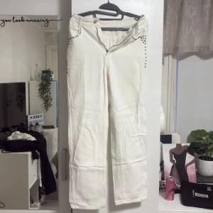 Vita raka jeans med nitar - Säljer ett par vita jeans med raka ben och coola nitar vid fickorna. De har klassisk midja och är tillverkade i ett stadigt bomullsmaterial. Perfekta för dig som vill sticka ut med detaljer och gillar en clean look.