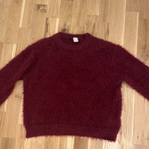 stickad tröja - Säljer en söt vinröd stickad tröja, den är tillverkad i ett mjukt, lurvigt material som känns riktigt cozy. Perfekt för dig som gillar en chill och trendig look😊