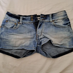 Blåa low waist jeansshorts  - Jättesnygga jeansshorts med många nyanser av blå. De är low waist och korta. Köpt från en marknad i Thailand.