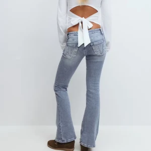 Gina Young 14* - Säljer ett par ljusblå bootcut jeans med snygga slitningar och broderade bakfickor. Jeansen har låg midja och klassisk femficksdesign, tillverkade i mjukt denim. Perfekta för dig som gillar retrovibbar och vill ha en cool siluett.
