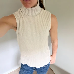 Ribbad poloväst - Snygg ribbad polotopp i ljus färg med hög krage och ärmlös design. 
